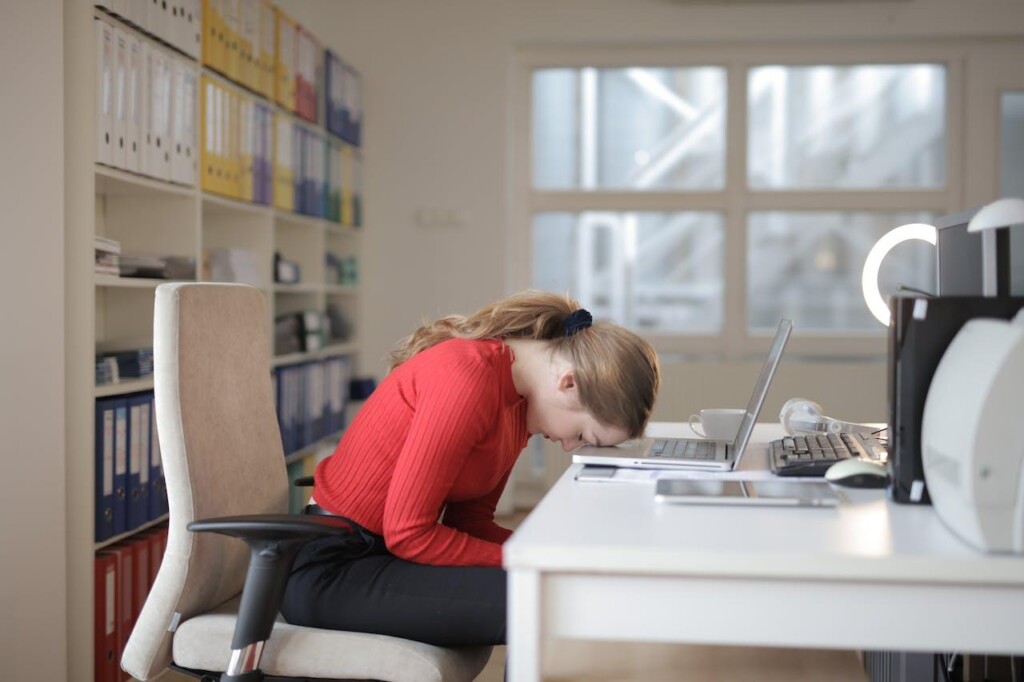 A Woman resting her forehead on a laptop